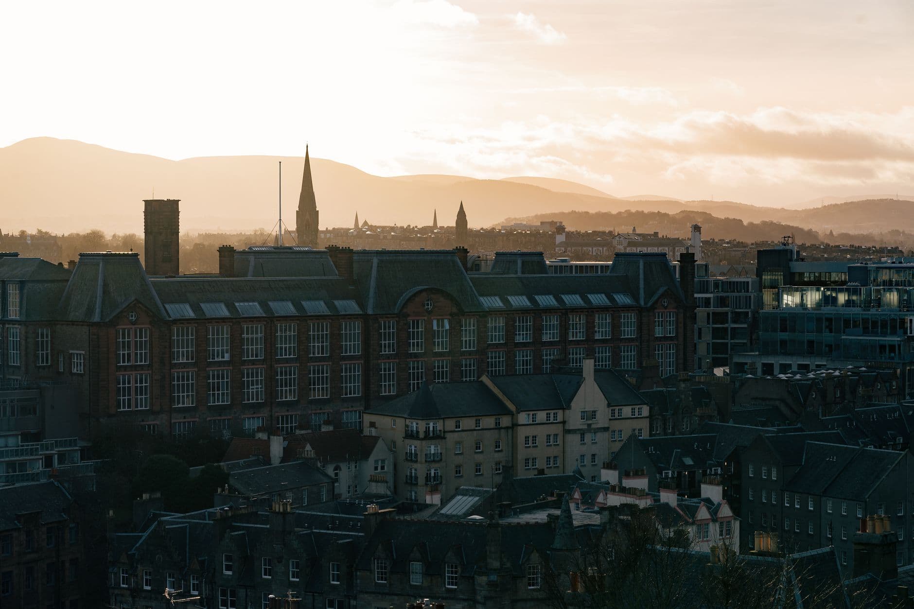 Scenic view of Edinburgh skyline with historic buildings and hills at sunrise.