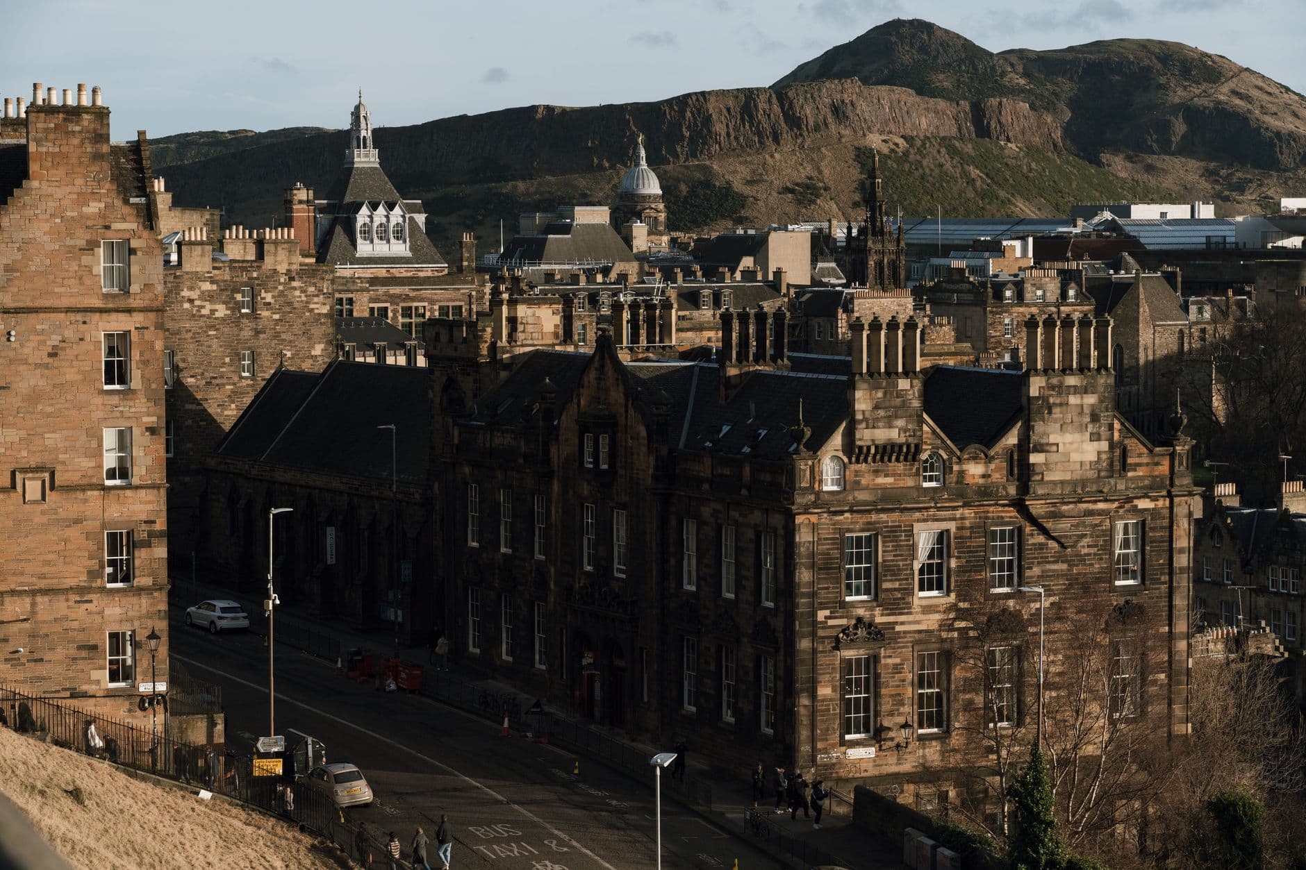 View of historic Edinburgh streets and buildings with Arthur's Seat in the background.