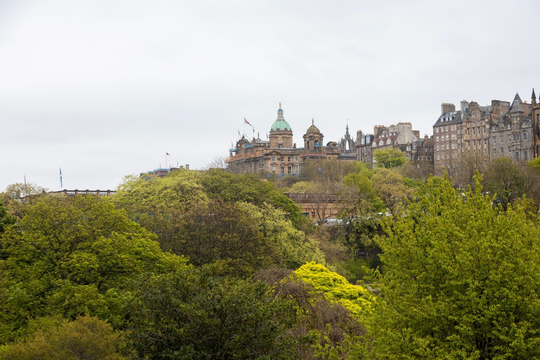 Beautiful view of Edinburgh's architecture surrounded by lush greenery on a cloudy day.